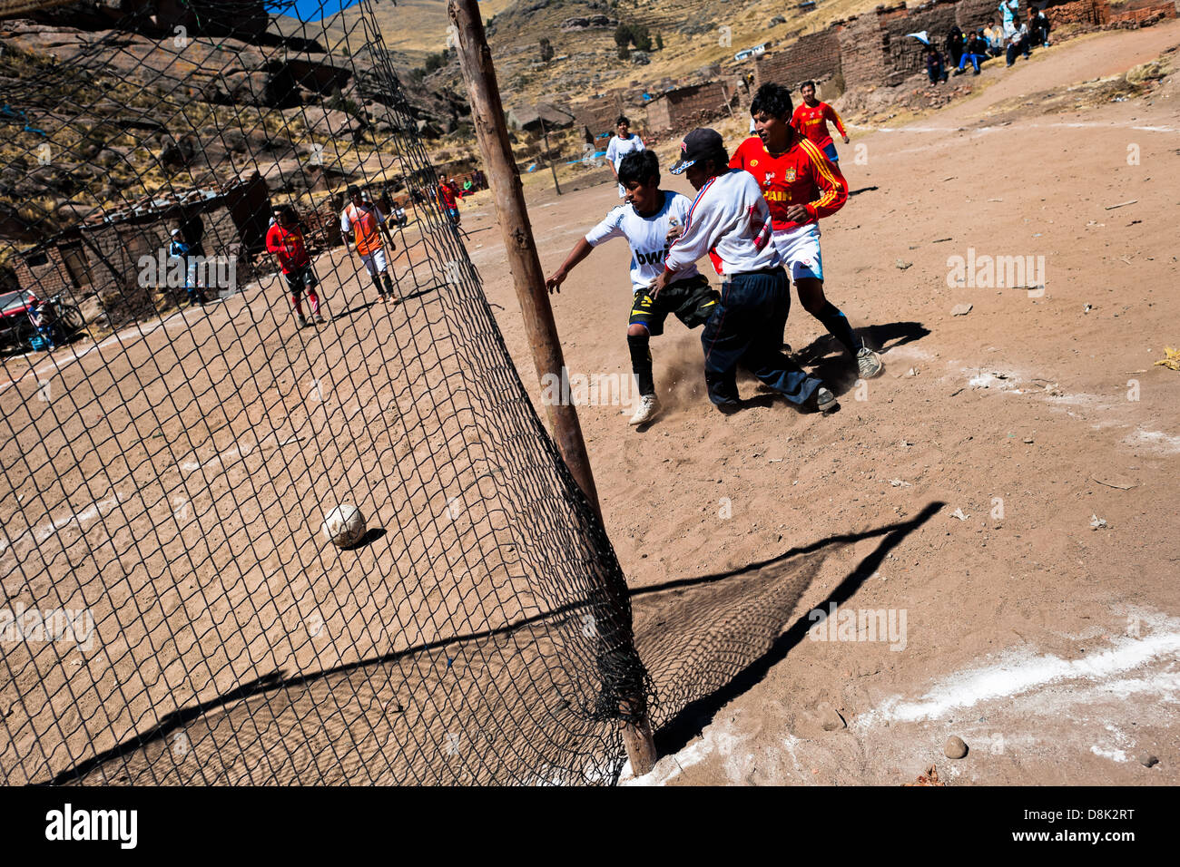 Einheimische Männer spielen Fußball auf einer staubigen Fußballfeld im ländlichen Berg Gemeinschaft in der Nähe von Puno, Peru. Stockfoto