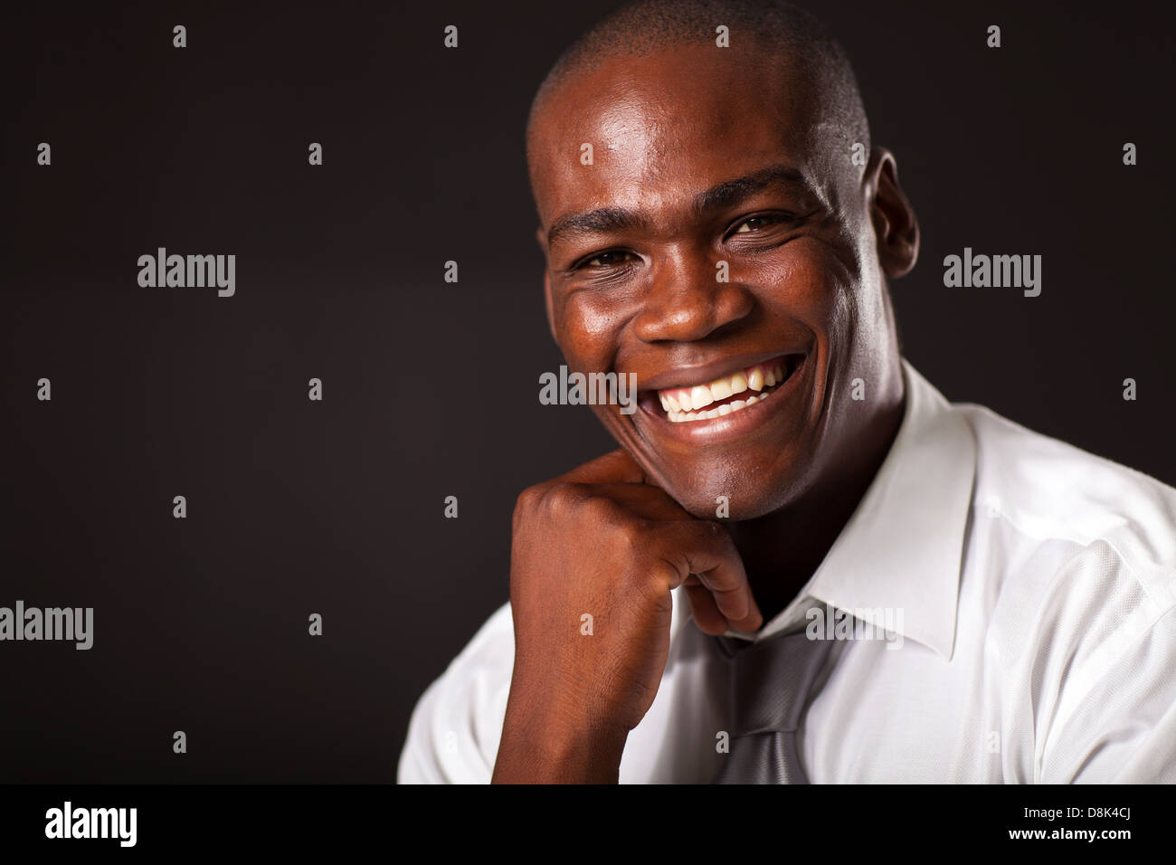 glücklicher afroamerikanischen jungen Mann Porträt über schwarzen Hintergrund Stockfoto