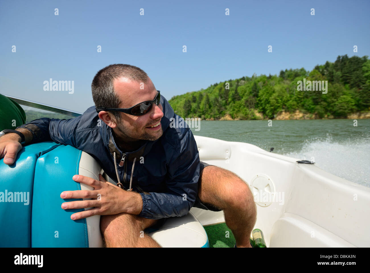 Mann in einem Motorboot Beschleunigung Weg entlang der Küste, hält dicht und lächelnd Stockfoto