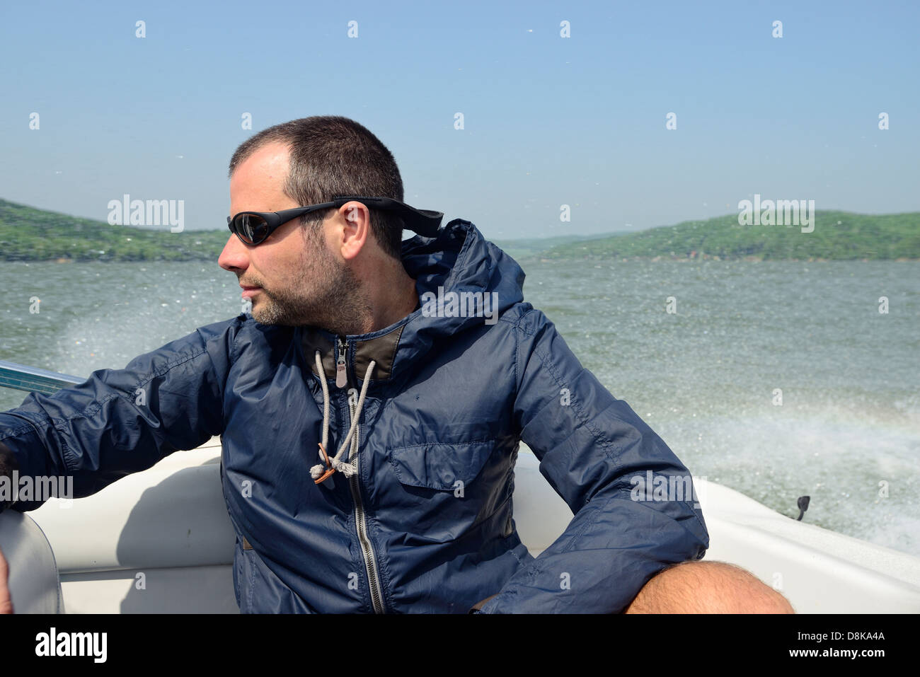 Mann in einem Motorboot entfernt entlang der Küste zu beschleunigen, festhalten und Überprüfung der Kokosblättern Stockfoto