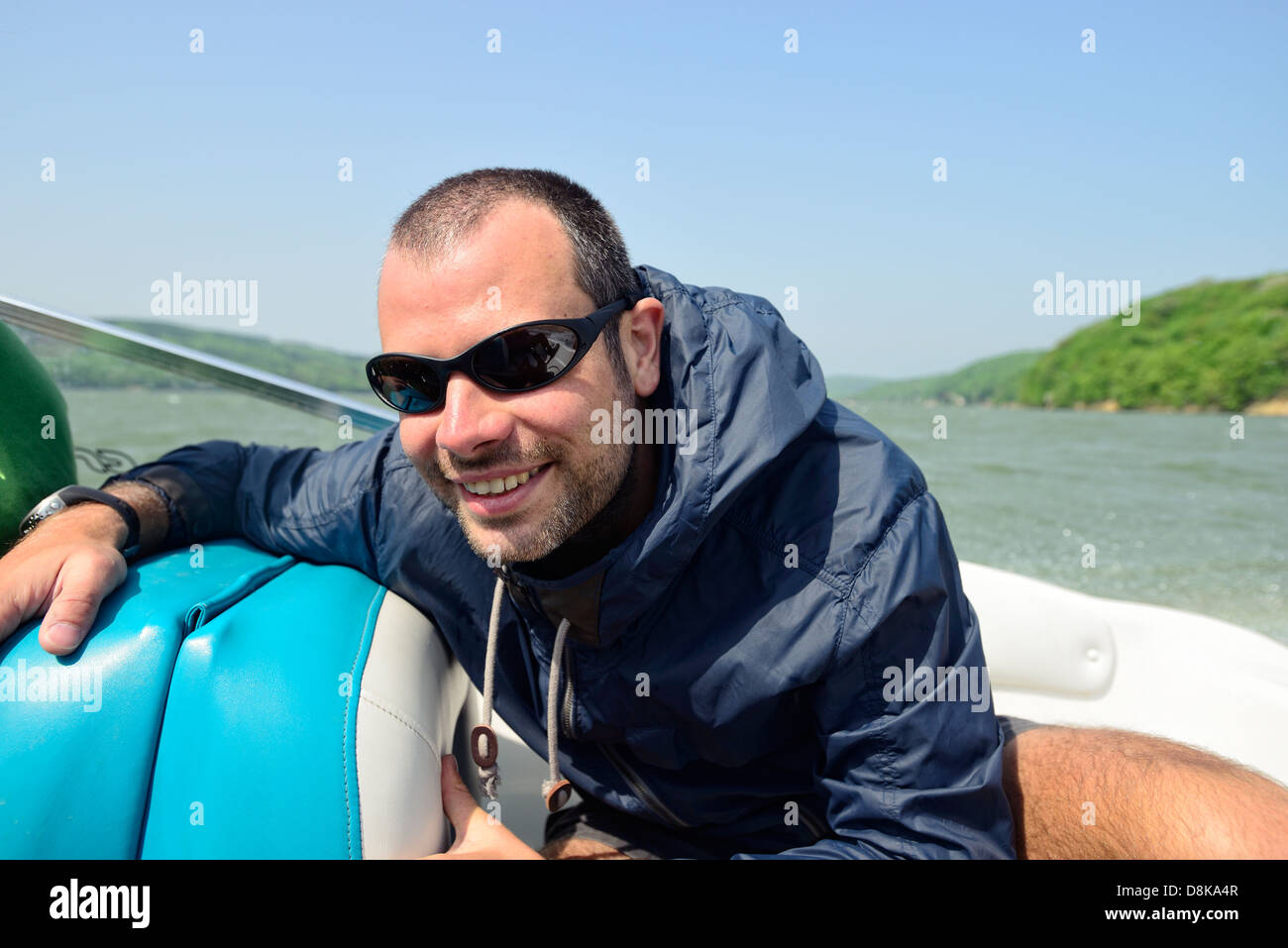 Mann in einem Motorboot Beschleunigung Weg entlang der Küste, hält dicht und lächelnd Stockfoto