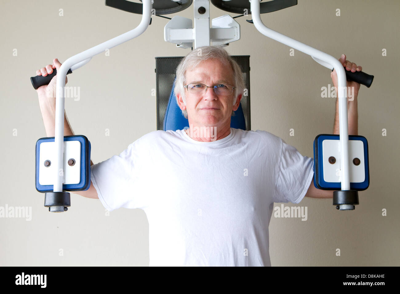 Älterer Mann im Ruhestand nutzt Krafttrainingsgeräte in einem Fitnessstudio, um seine Gesundheit und sein Leben zu verbessern. Stockfoto