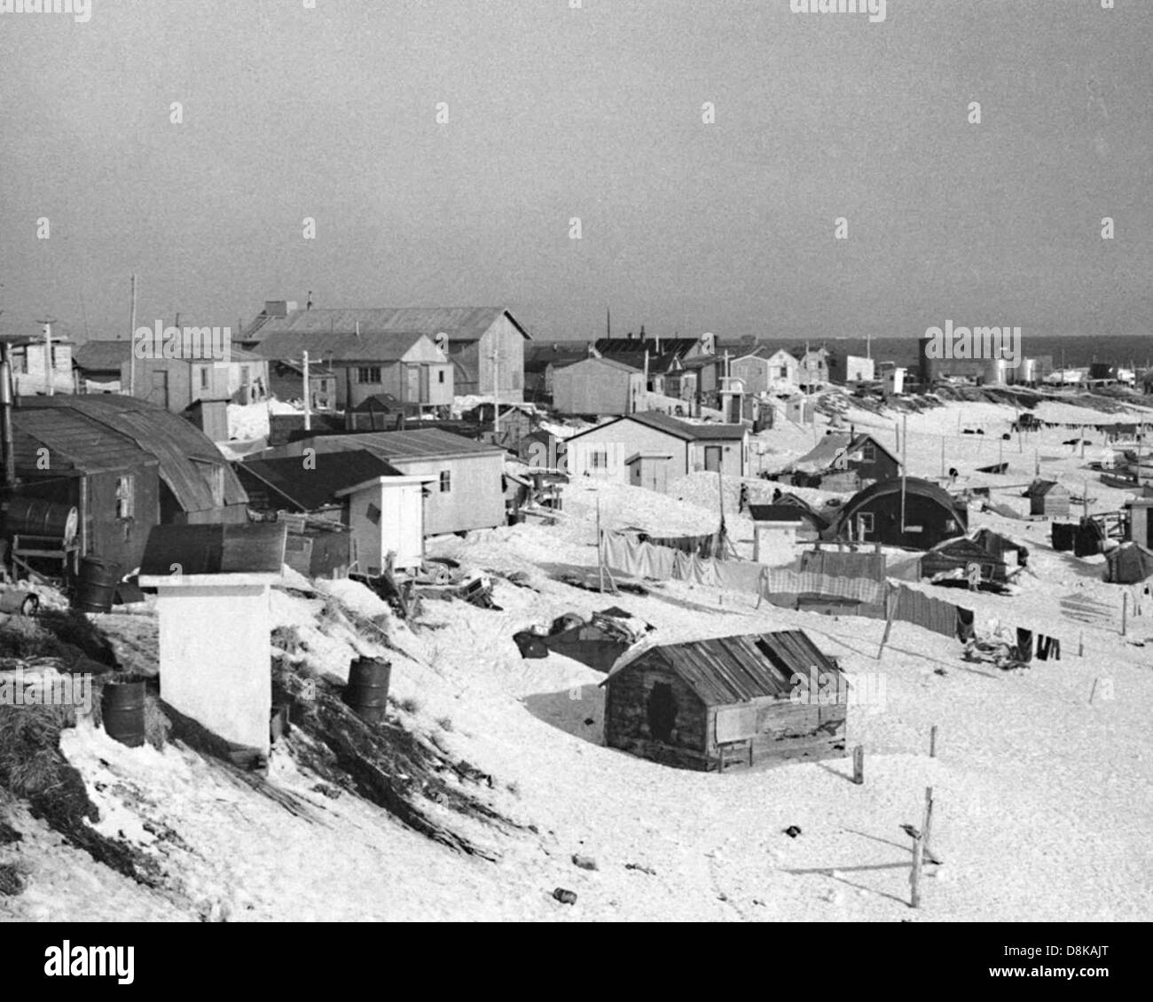 Ein Vintage-Foto, das eine friedliche Winterszene auf dem Land mit schneebedeckten Feldern und rustikalen Gebäuden zeigt. Stockfoto