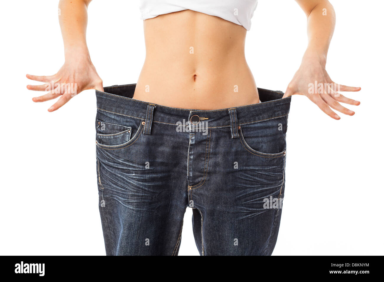 Frau zeigt ihre Taille durch das Tragen einer alten Jeans, isoliert auf weiss Stockfoto