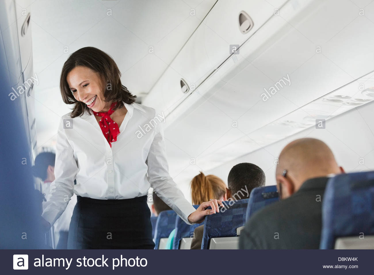Flight Attendant im Gespräch mit Passagieren im Flugzeug Stockfoto