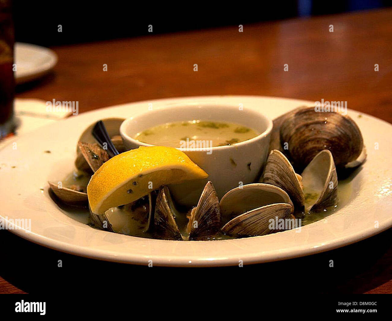 Eine Schüssel mit gedämpften Venusmuscheln, die in einer geschmackvollen Brühe serviert werden. Die Venusmuscheln sind prall und zart, schwimmen in einer reichhaltigen, aromatischen Flüssigkeit, ideal für Meeresfrüchte-Liebhaber oder eine angenehme Mahlzeit. Stockfoto