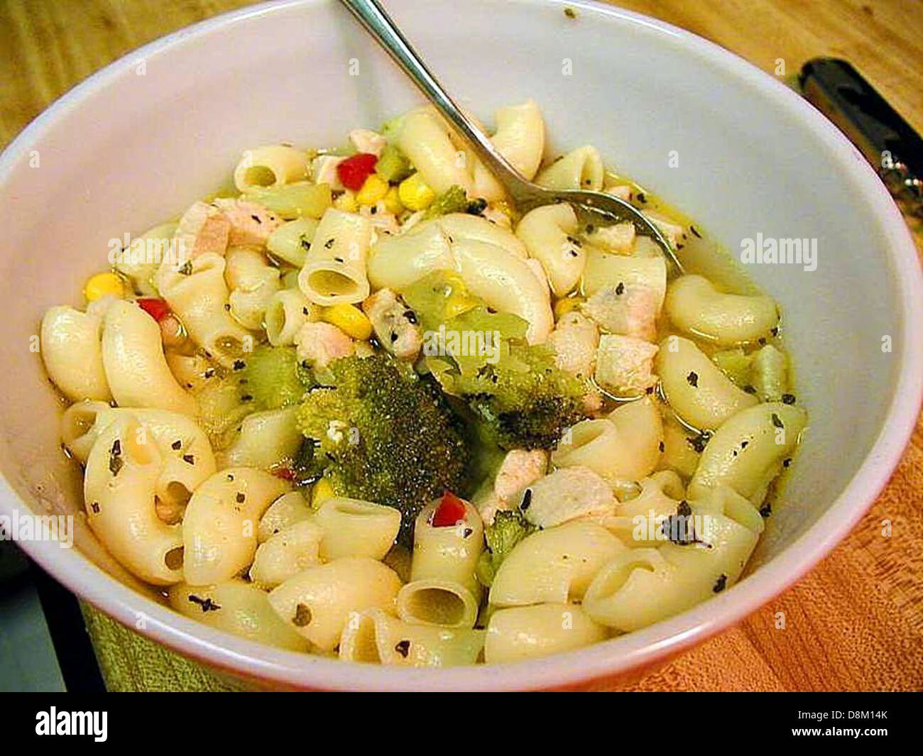 Eine Schüssel mit dampfender Hühnernudelsuppe mit zarten Hühnerstückchen, Nudeln und Gemüse in einer aromatischen Brühe, die eine angenehme und nahrhafte Mahlzeit bietet. Stockfoto