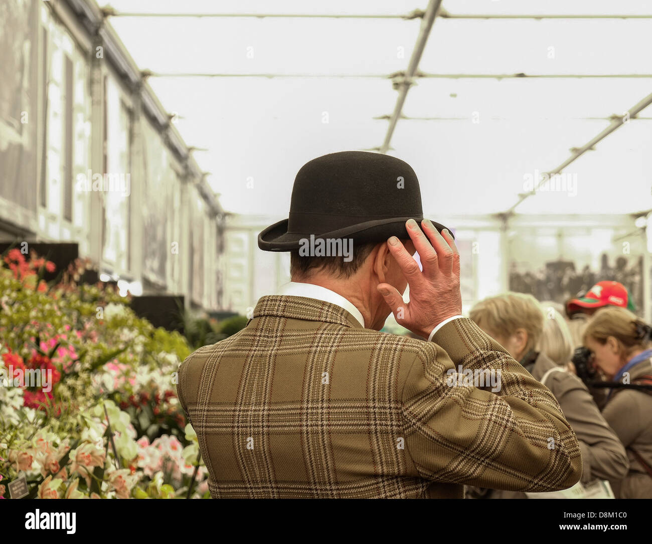 Ein Mann, der bei der Chelsea Flower Show in London in Großbritannien seine Bowler-Mütze umstellt. Stockfoto