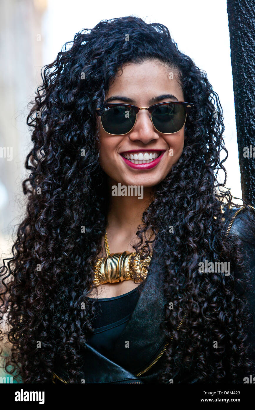 Porträt einer schönen schwarzen Frau mit lockigen langen Haaren, Sonnenbrille und lächelnd, London, England, UK. Stockfoto