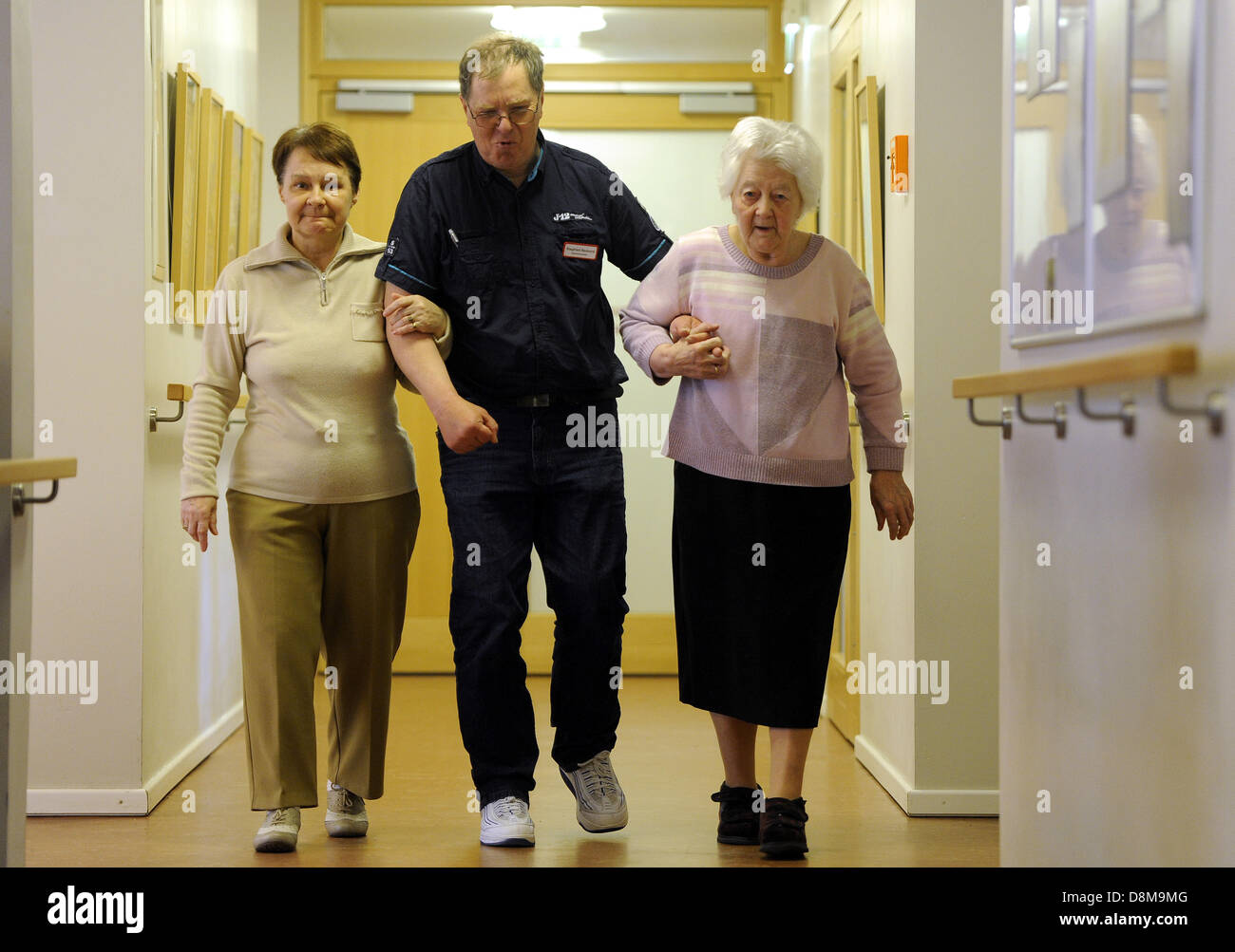 Siegfried Bednors geht auf einen Flur mit zwei alten Frauen im Haus für Menschen mit Demenz. Der geistig Behinderte Mann ist eine gute Seele für den kranken Menschen in das "Haus im Park" in Bremerhaven (Bremen), Deutschland. Stockfoto