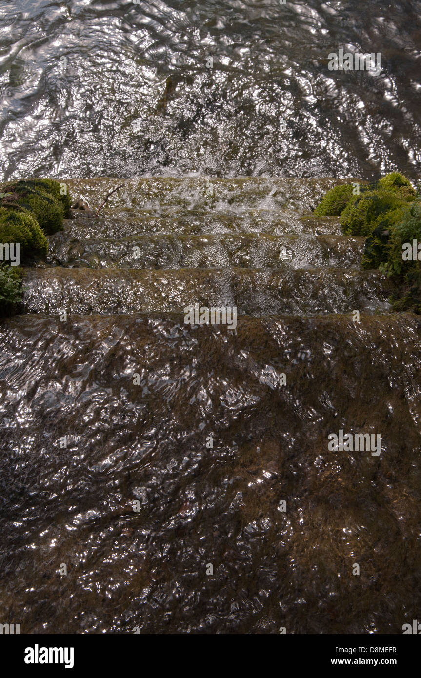 Wasser-Feature mit dem Plätschern des Wassers fließt über Steinstufen, Ansicht von oben Schritte, sonnendurchfluteten, glitzernden, Wellen, Kaskadierung Stockfoto