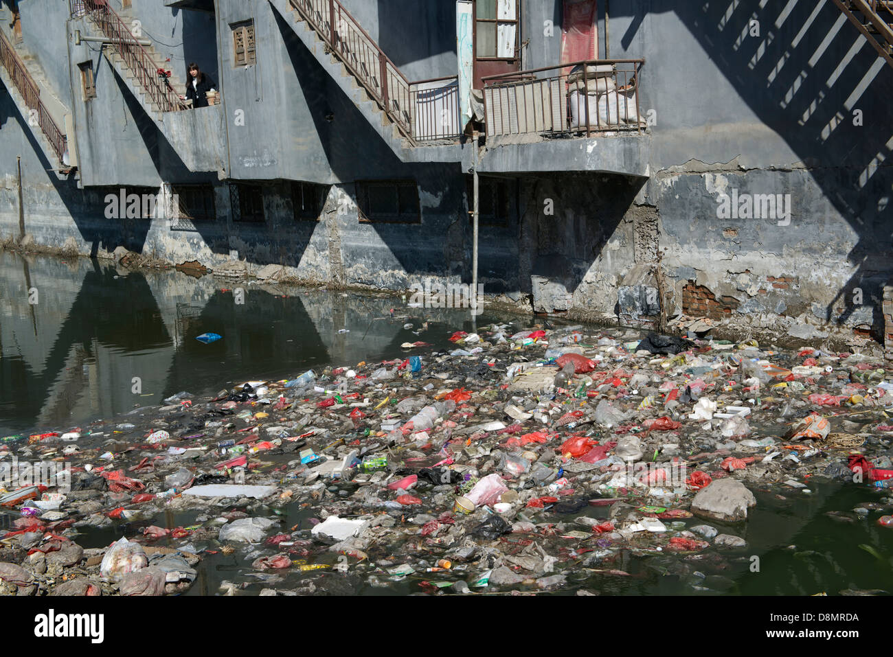Liu Lu, Einheimische Bewohner, steht auf einem Balkon über einen stark verschmutzten Fluss von Müll und industriellem Abwasser in Shengfang. Stockfoto