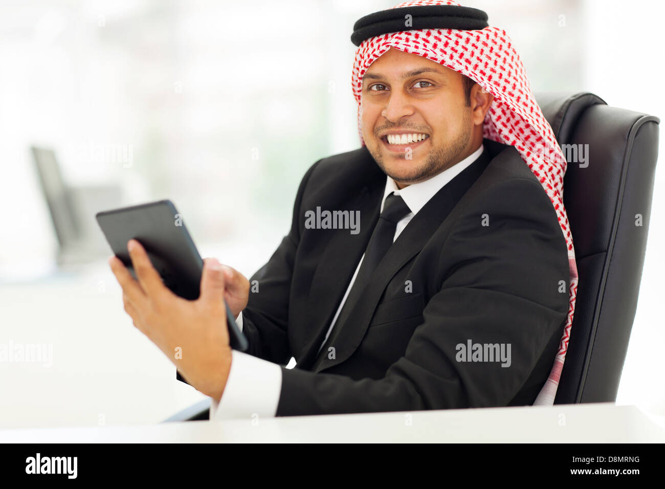 fröhlich-arabischer Milliardär Surfen Internet auf seinem Tablettcomputer Stockfoto