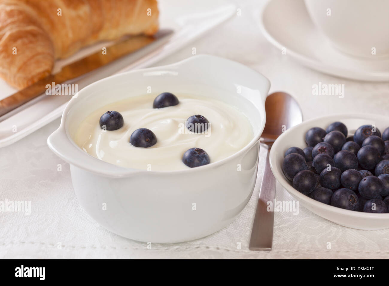 Joghurt und Bluberries Frühstück - Joghurt mit Blaubeeren zum Frühstück mit Kaffee und Croissant. Stockfoto