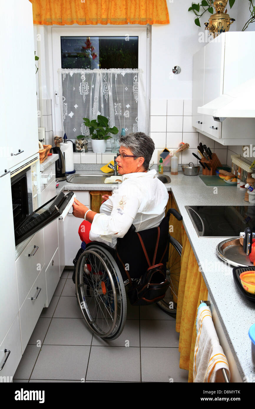 Frau in einem Rollstuhl in der Küche Stockfoto