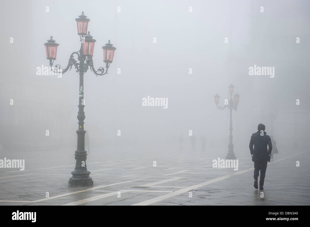 Ein Mann geht in St. Markus Platz In Venedig in dichtem Nebel, Italien abgedeckt. Stockfoto