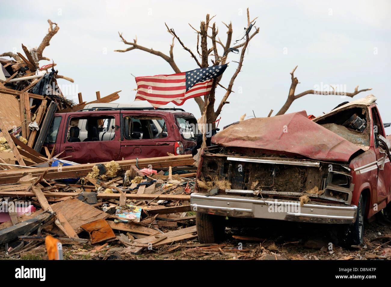 Eine amerikanische Flagge flattert unter die Überreste von Häusern im Anschluss an eine EF-5 Tornado 25. Mai 2013 in Moore, Oklahoma. Die massiven Sturm mit Windgeschwindigkeiten von mehr als 200 Meilen pro Stunde Riss durch den Oklahoma City Vorort 20. Mai 2013, mindestens 24 Menschen getötet, mehr als 230 verletzte und Tausende verdrängen. Stockfoto