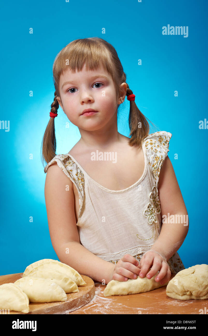 Lächelnd wenig Mädchen kneten Teig in Küche mit eine Torte backen Stockfoto