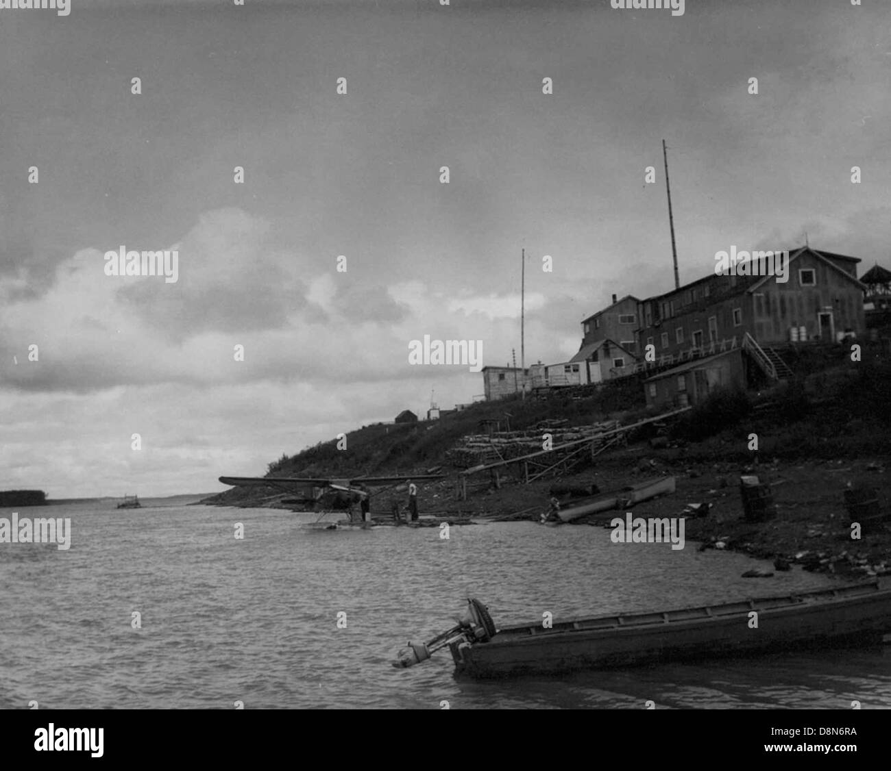 Schwarz / weiß Foto von Haus an der Küste mit kleinen Boot in Foregournd und Wasser-Ebene im Hintergrund. Stockfoto