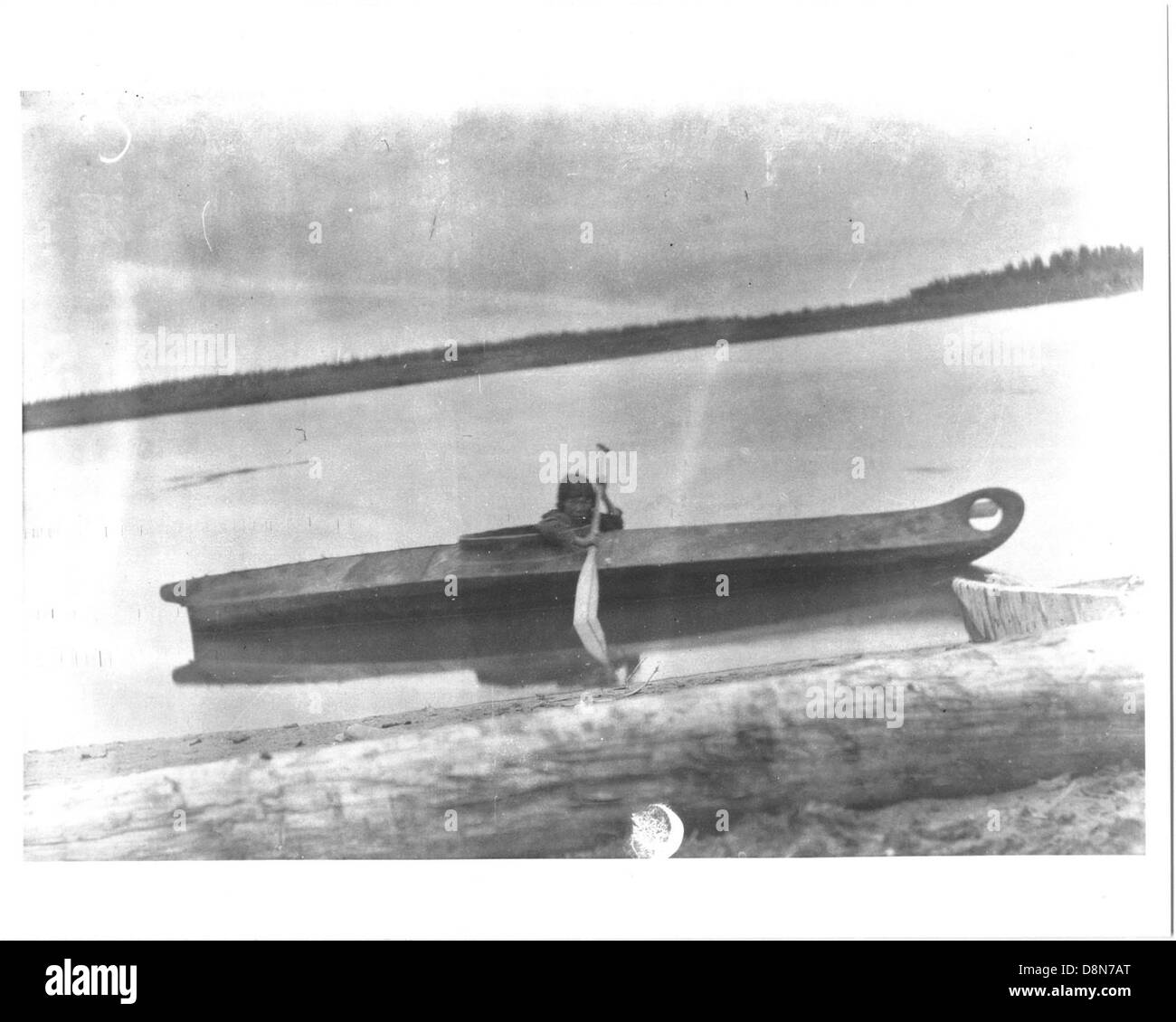 Ein Eskimo-Junge paddelt mit einem traditionellen Kajak durch ruhiges Wasser. Das aus natürlichen Materialien hergestellte Kajak wird für die Jagd und den Transport in arktischen Regionen verwendet und spiegelt das kulturelle Erbe des Jungen wider. Stockfoto