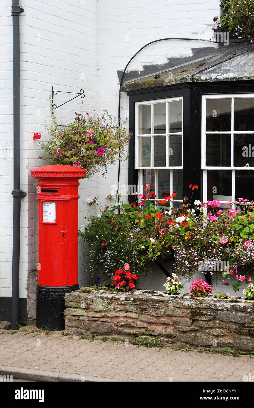 Englisch Red Post Box neben Körbe mit bunten Blumen Stockfoto