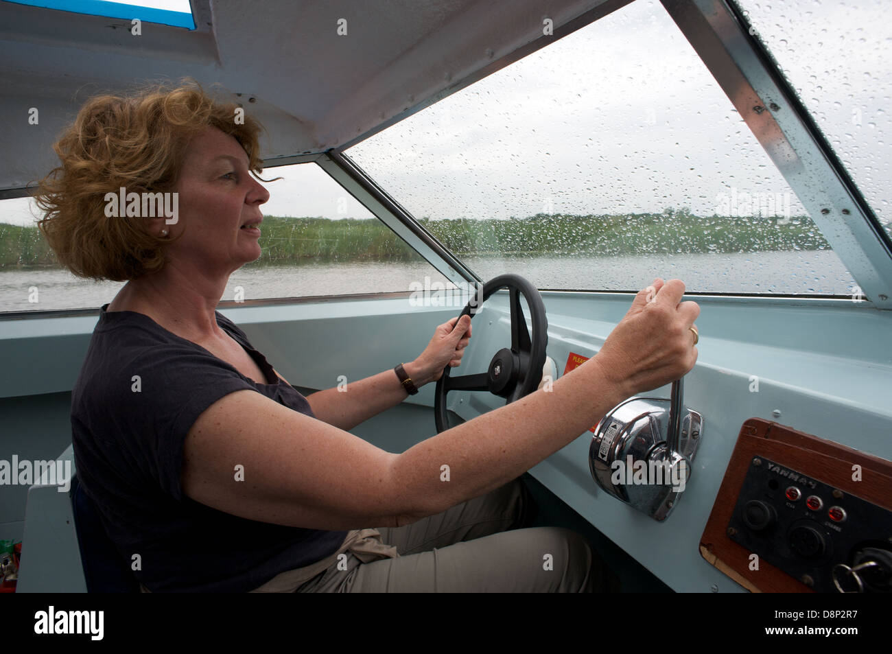Frau am Steuer von einem Motorboot auf den Norfolk Broads UK Stockfoto