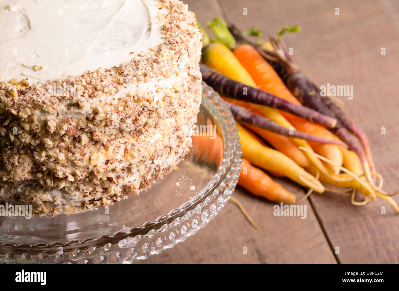 Karotte-Kuchen mit Nüssen und frischen Karotten im Hintergrund gefrostet Stockfoto