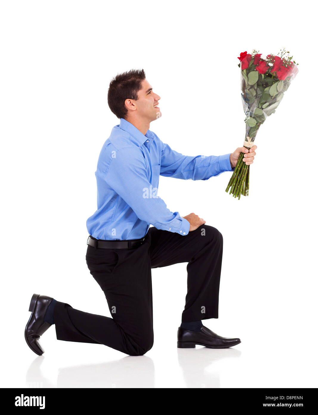 junger Mann Knie abwärts auf Boden und geben Rosenstrauss isoliert auf weiss Stockfoto