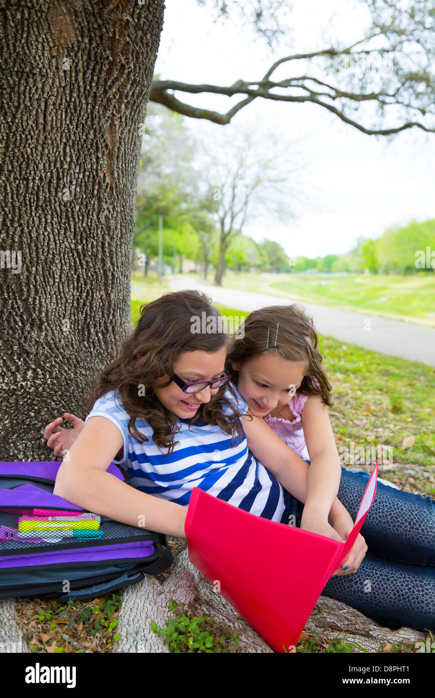 Schwester Freunde Mädchen entspannt unter Baum Park nach der Schule mit Tasche und Ordnern Stockfoto