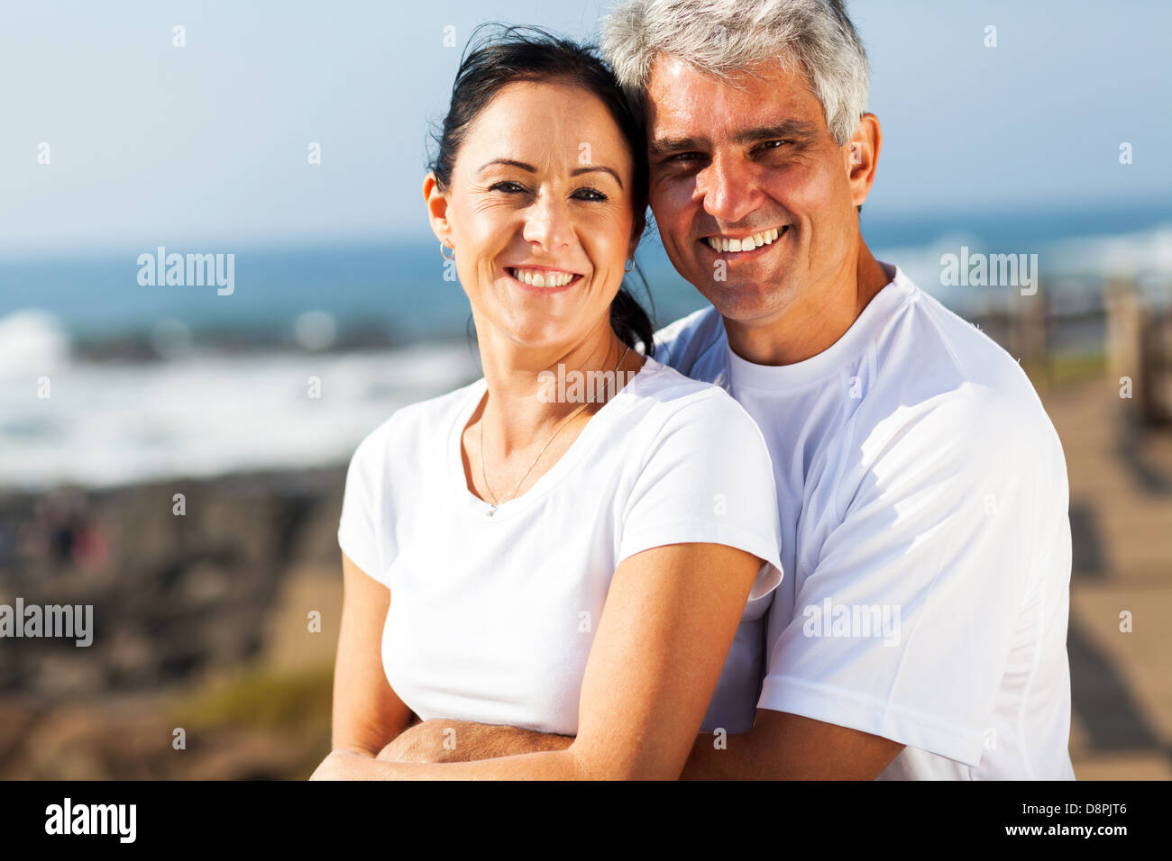 Porträt des mittleren gealterten paar umarmt am Strand Stockfoto