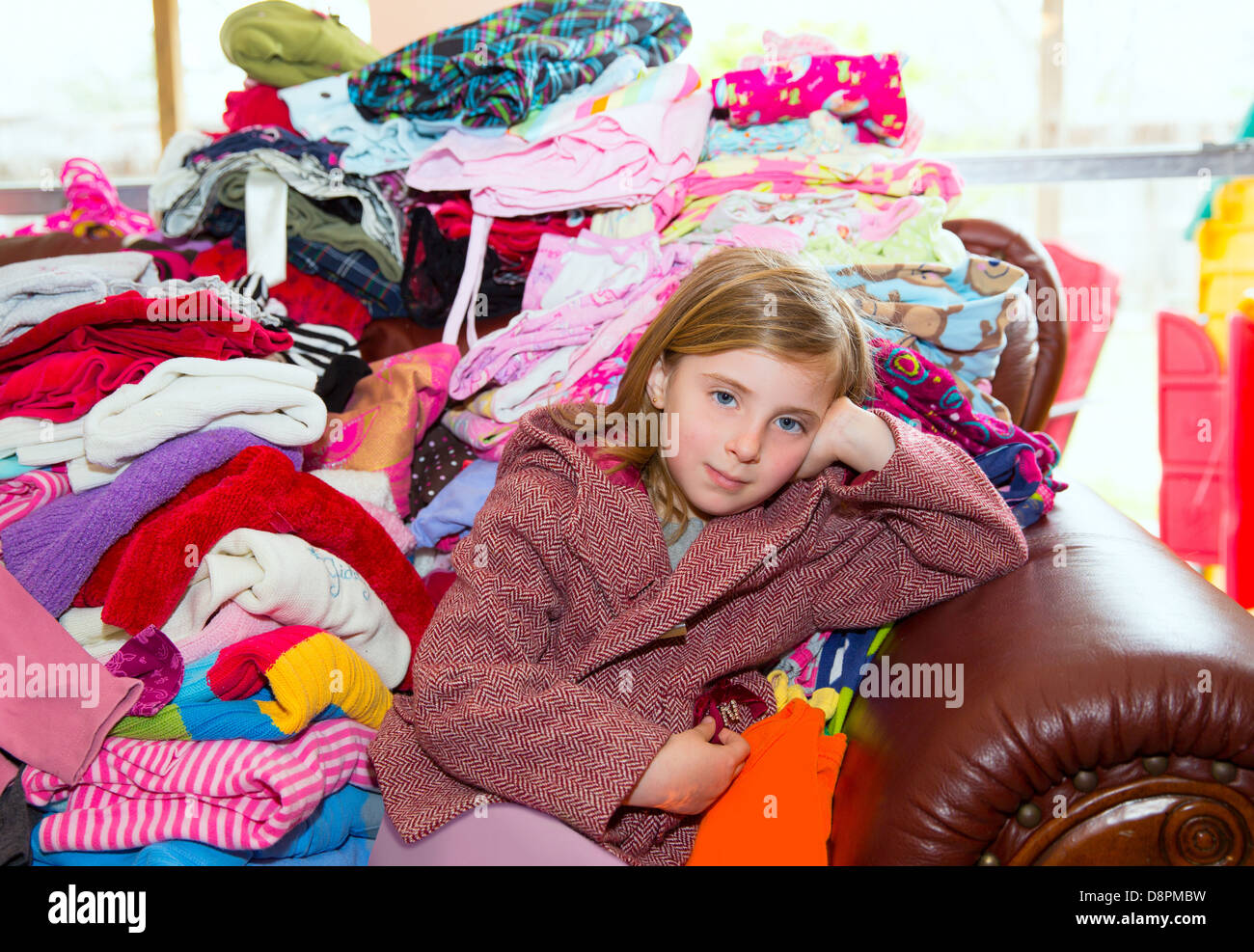 Blondes Kind Mädchen sitzen auf einem Sofa unordentliche Kleidung Spielbetrieb Wäsche Stockfoto