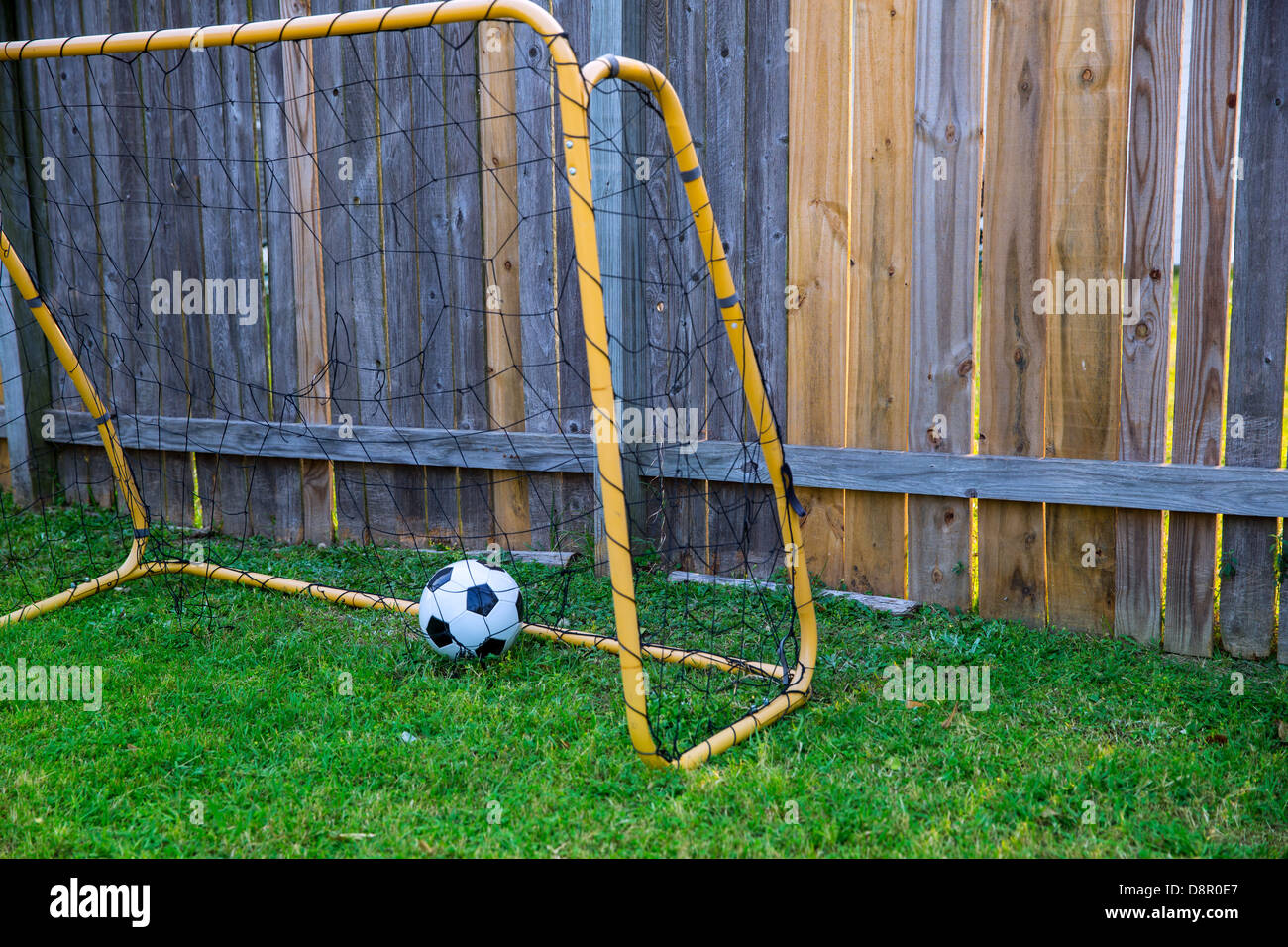 Hinterhof-Kinder-Fußballtor am Holzzaun mit Lederball auf Rasen Stockfoto