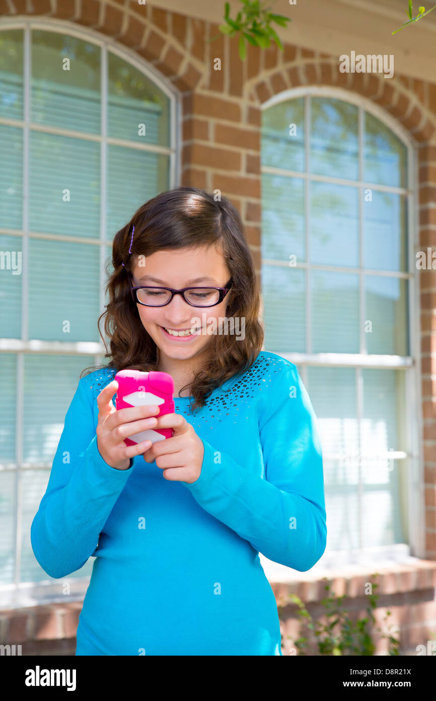 Teenager-Mädchen mit Brille mit rosa Smartphone lächelnd zu spielen Stockfoto