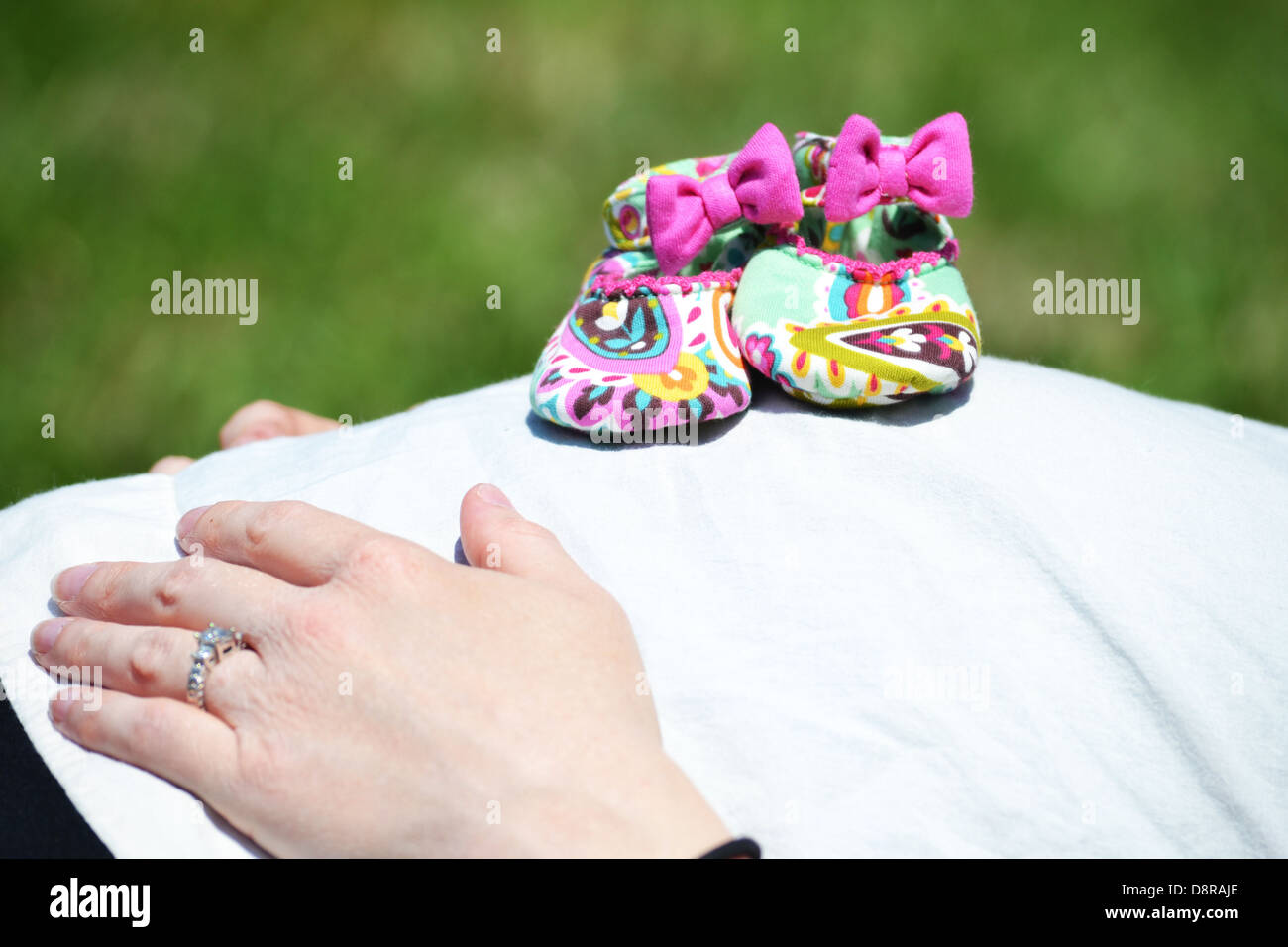 Vera Bradley Babyschuhen auf Mamas Babybauch. Stockfoto