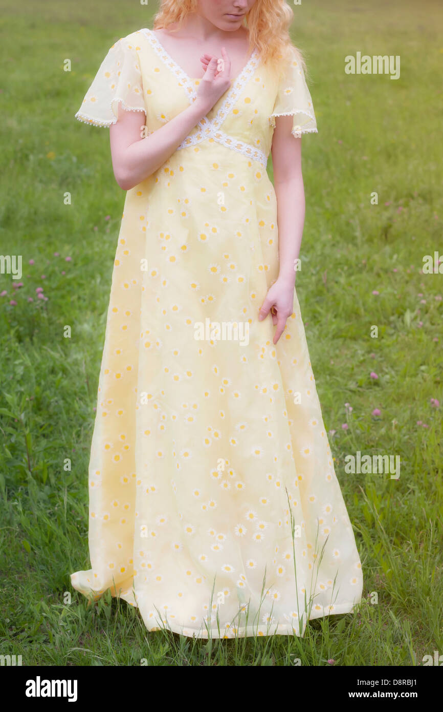 eine blonde Frau in einem gelben Kleid auf einer Wiese Stockfoto