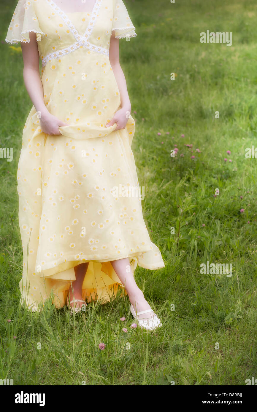 eine Frau in einem gelben Kleid auf einer Wiese Stockfoto