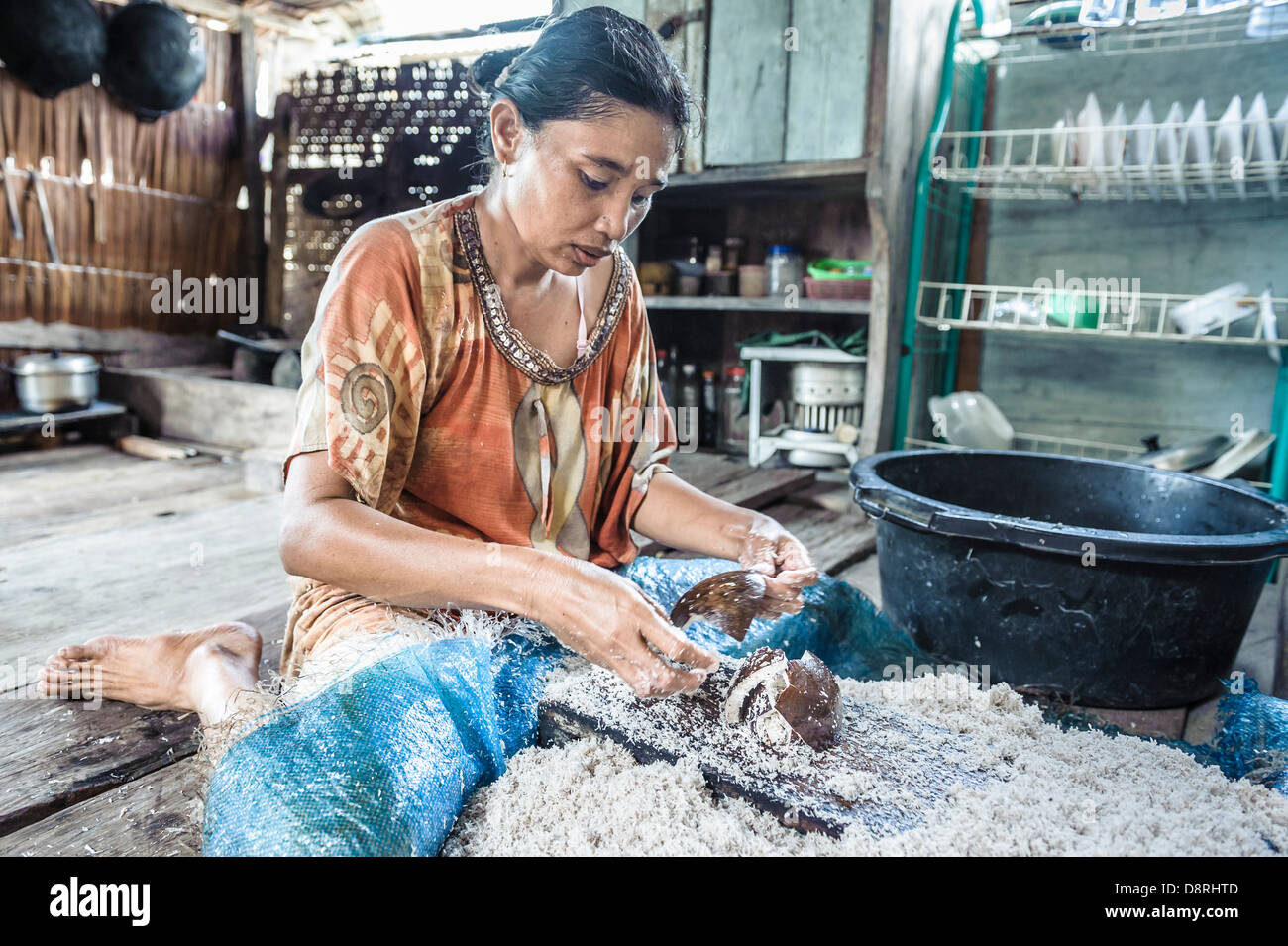 Bajau Frau Gitter Kokosnuss in eine einfache Küche, Togean-Inseln, Indonesien, Asien Stockfoto