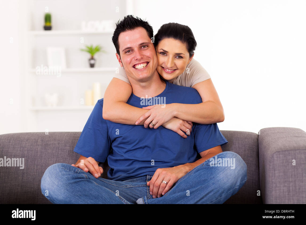 junge liebende Paar umarmt zu Hause auf sofa Stockfoto