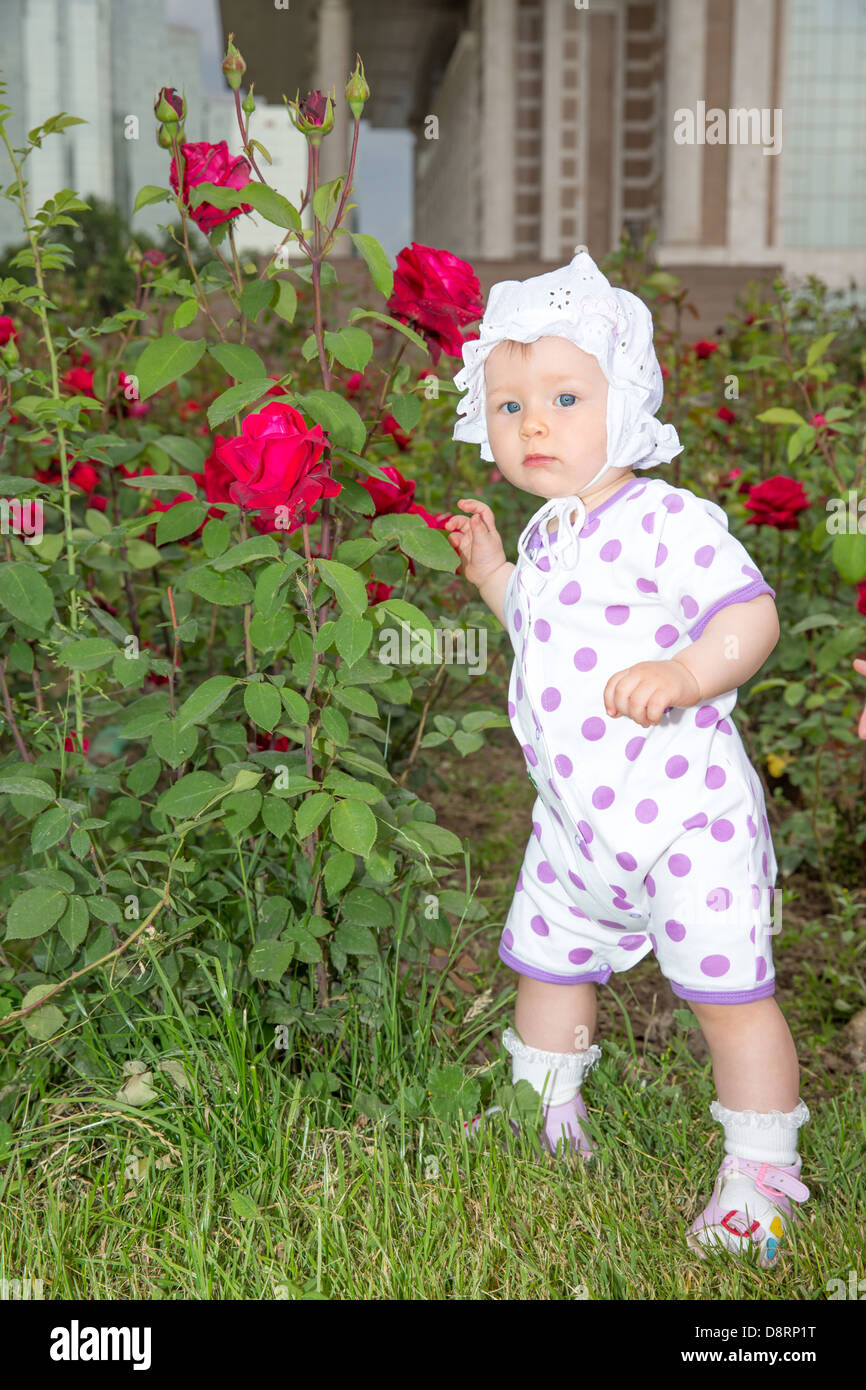 Lächelndes hübsches kleines Kind Mädchen mit Blume rose im park Stockfoto