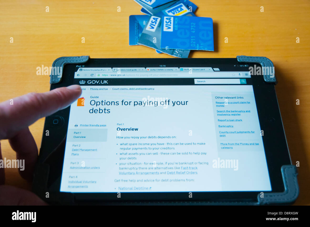 Person, die in UK Debt Relief Informationen über Internet auf dem Ipad Mini Tablet PC zu Hause Stockfoto
