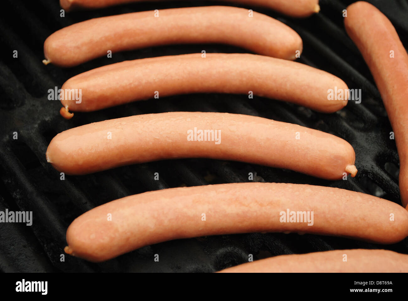 Mehrere Raw Hotdogs auf einem Sommer-Grill Stockfoto
