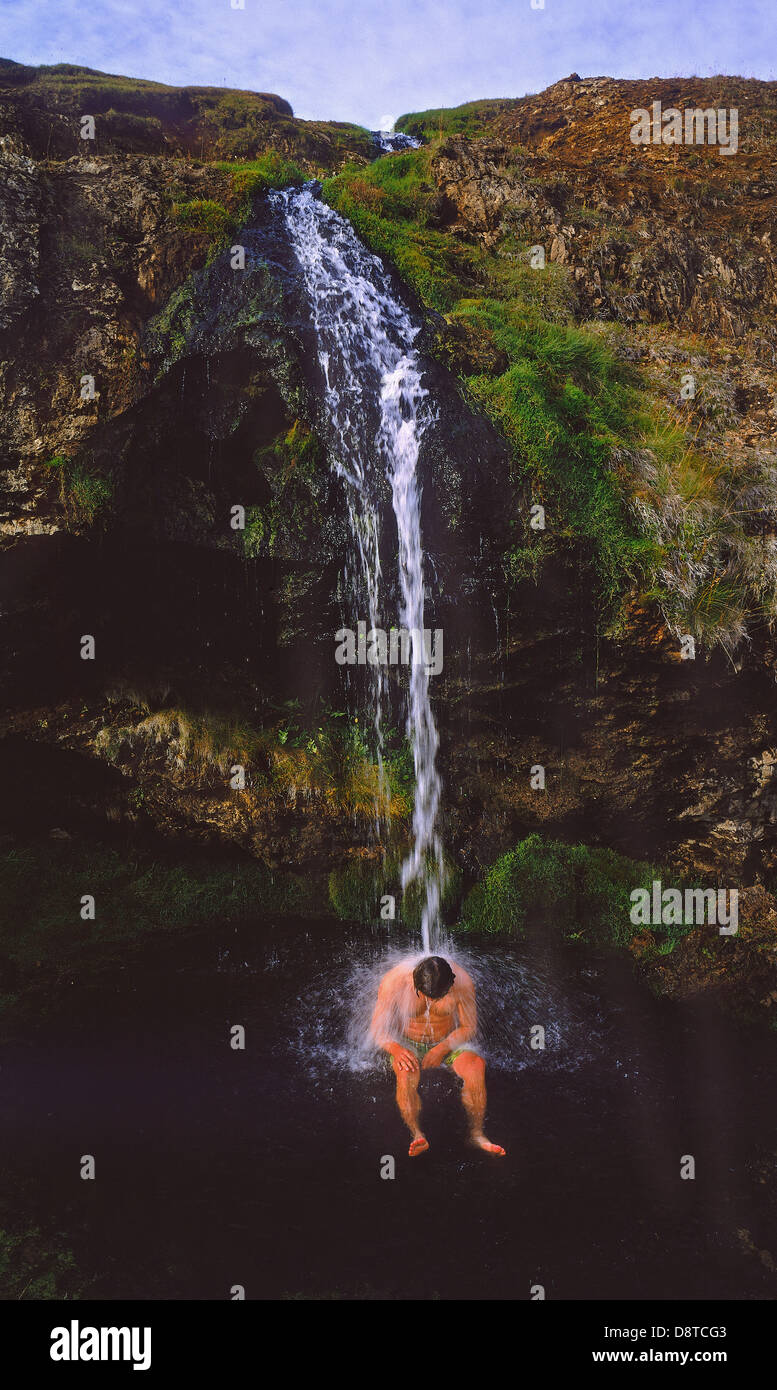 Mann unter warmen Wasserfälle, Hochland, Island Stockfoto