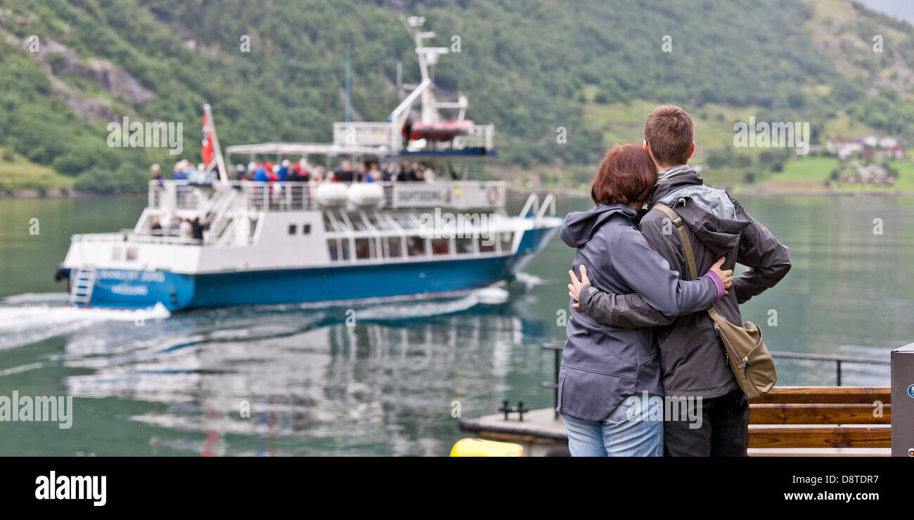 Paar auf der Anklagebank beobachten Ausflugsboot, Geirangerfjord, Norwegen. Stockfoto