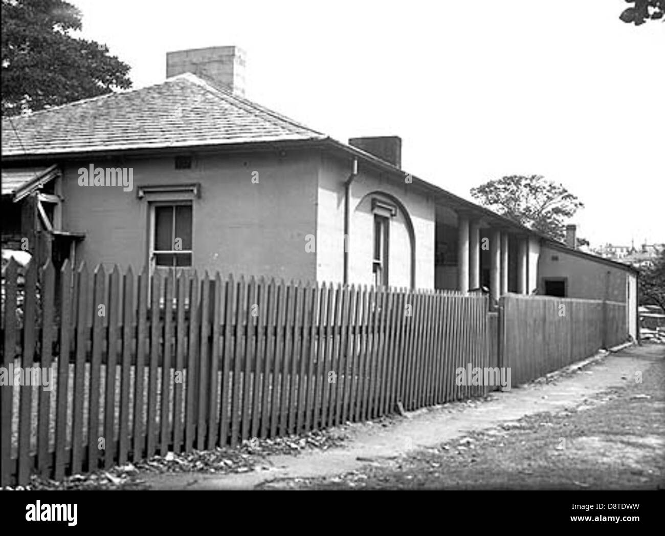 Dieses historische Foto aus dem Jahr 1838 zeigt ein Gebäude auf Goat Island in New South Wales, Australien. Das Bild zeigt den architektonischen Stil der Zeit, zusammen mit den Kasernen und Quartieren, die von den Arbeitern und Sträflingen genutzt wurden, die einst die Insel bewohnten. Stockfoto