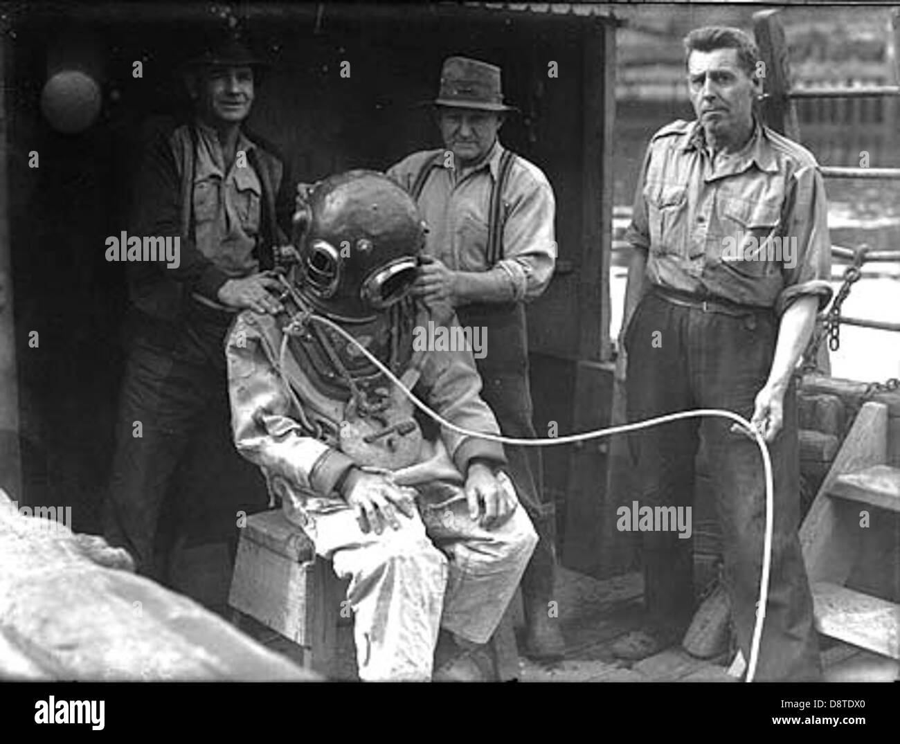 Dieses Schwarzweiß-Foto aus den Archiven der State Records NSW zeigt einen Taucher mit Schutzhelm, der in maritimen Dienstleistungen tätig ist, und hebt die spezialisierte Tauchausrüstung und die Rolle von Tauchern in der frühen maritimen Industrie in New South Wales hervor. Stockfoto