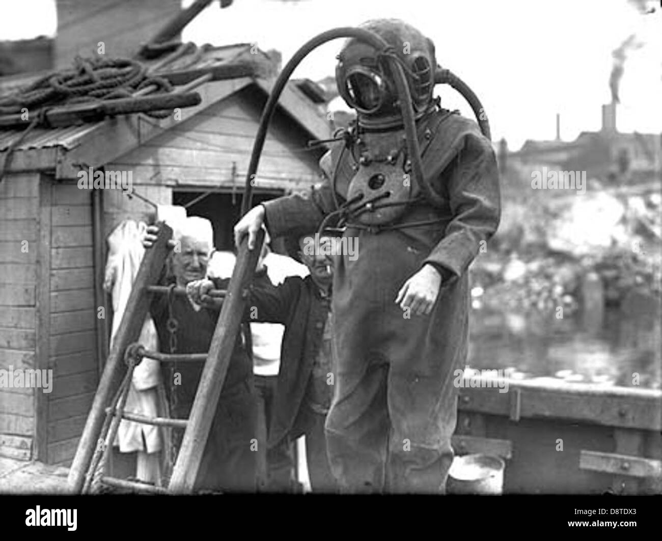 Dieses Foto aus dem New South Wales State Archives zeigt einen Taucher mit Schutzhelm, ein wesentlicher Bestandteil der Seeschifffahrt, der Unterwasseraktivitäten unternimmt. Der Taucher ist mit traditioneller Tauchausrüstung für Unterwasseraufgaben ausgestattet. Stockfoto