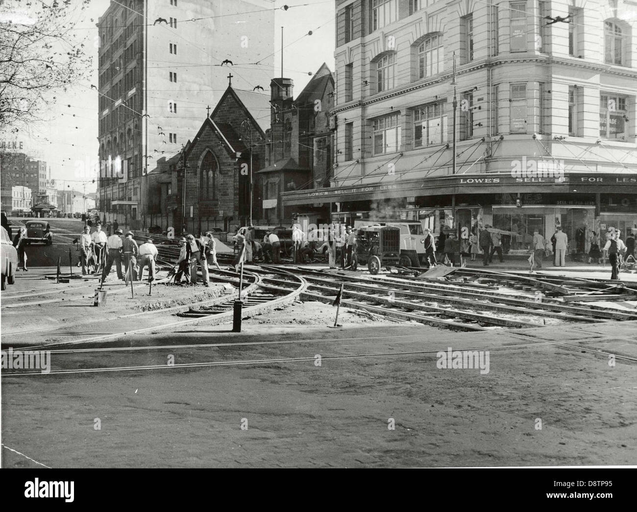 Dieses Schwarzweiß-Foto zeigt Arbeiter, die Straßenbahnschienen entlang der George Street in Sydney verlegen. Es erfasst die historische Transformation der städtischen Infrastruktur und spiegelt die Entwicklung der Stadtentwicklung im frühen 20. Jahrhundert wider. Stockfoto