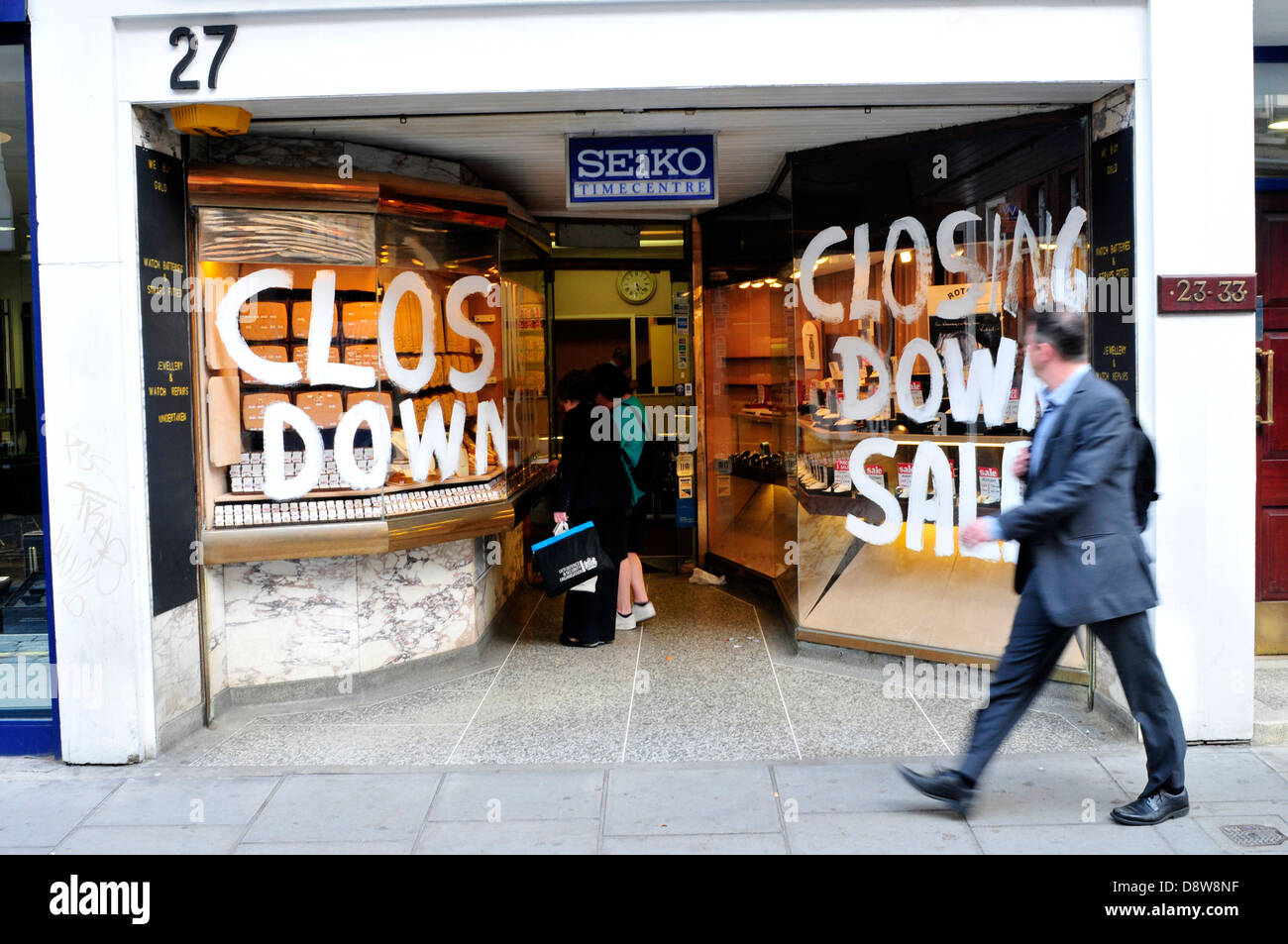 Frauen auf der Suche an einem Juweliergeschäft Fenster mit einem 'Schließung' Zeichen. Zentral-London, UK Stockfoto
