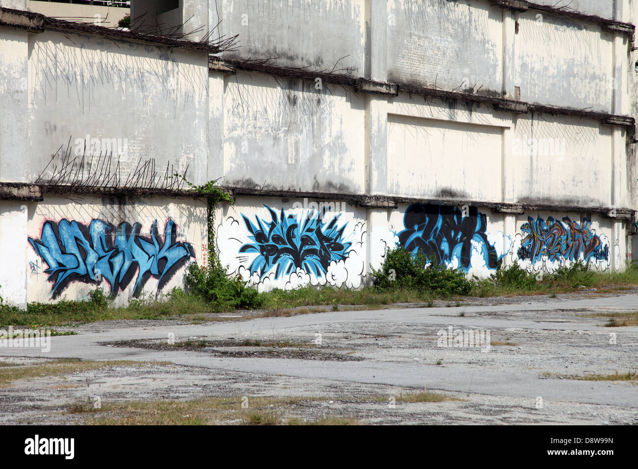 Es ist ein Foto von einer blauen Graffiti gegen eine zerstörte Wand in einer Einöde einer Stadt in Malaysia. Wir können sehen, dass es ein Industriegebiet ist Stockfoto
