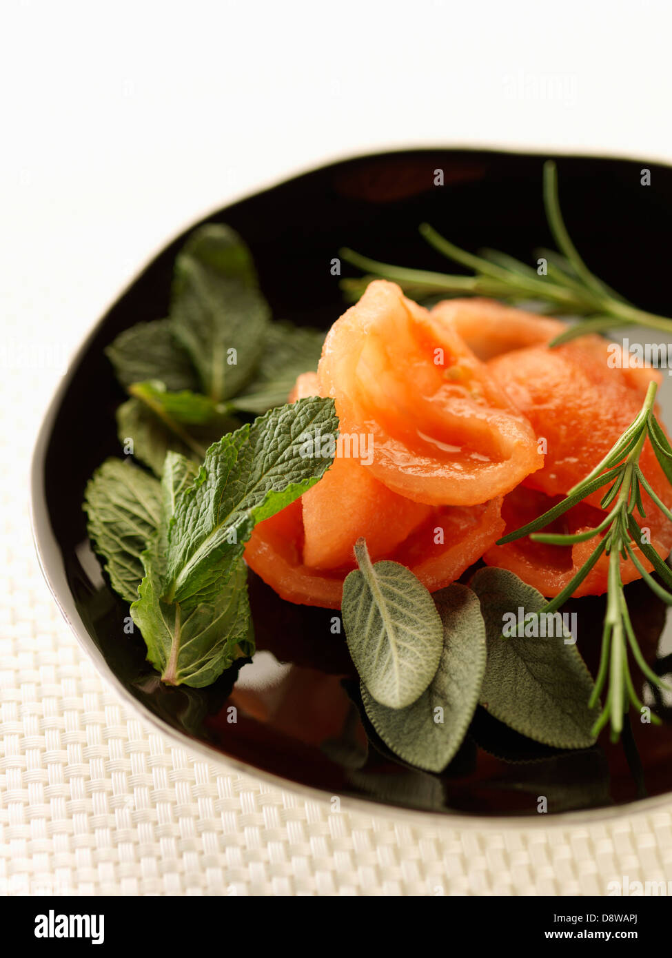 Teller mit geschälten Tomaten, Minze, Salbei und Rosmarin Stockfoto